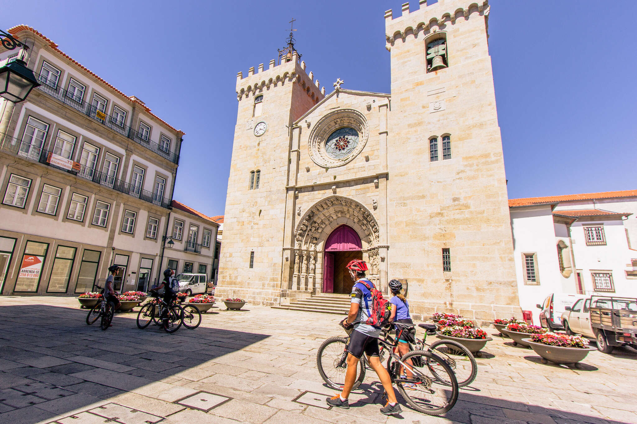 Cyclists admire a church as they push their bikes.
