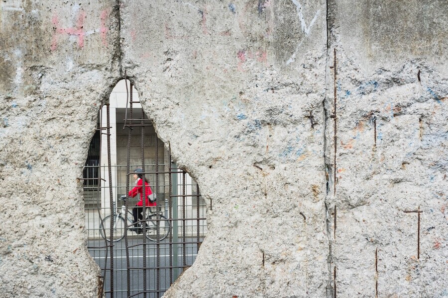Lady seen cycling through a gap in the Berlin Wall, Germany. Morgana Bartolomei@Unsplash